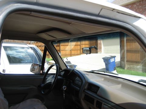 1993 Ford Bronco — Interior of a white 1992 Ford F-150 viewed from passenger side, showing dashboard, steering wheel, and sun vi…