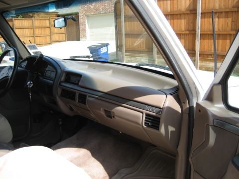 1993 Ford Bronco interior showing dashboard, steering wheel, and passenger side door frame. XLT badge visible