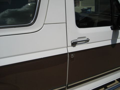 Side view of a white and brown Ford Bronco door with chrome handle