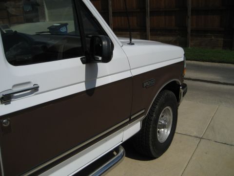 White and brown 1993 Ford Bronco, front passenger side, chrome door handle, side mirror, and running board