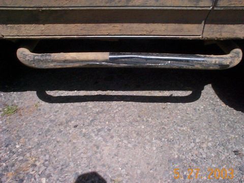 1983 Ford Bronco - A close-up of a worn side step on a dirty vehicle, parked on gravel.