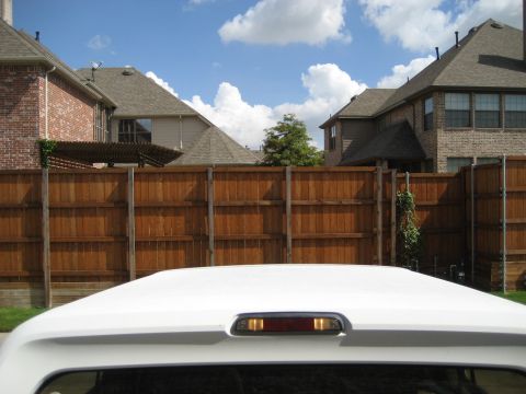 1993 Ford Bronco - The top of a white vehicle is shown against a backdrop of houses and a wooden fence under a cloudy sky.