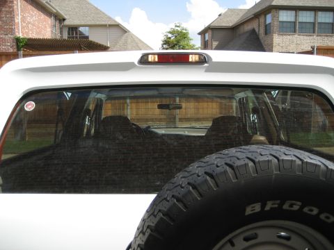 1993 Ford Bronco - Rear view of a white 1993 Ford Bronco, showing the spare tire and tinted windows.