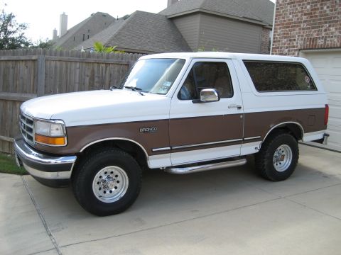 1993 Ford Bronco - This two-tone 1993 Ford Bronco is parked in front of a garage and wooden fence.