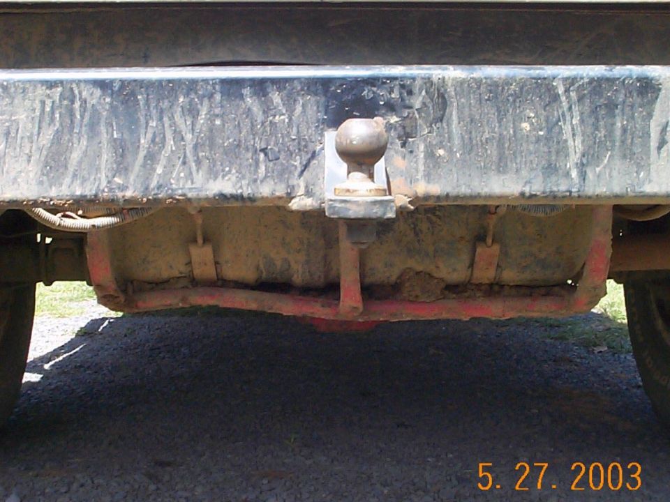 Trailer hitch ball on muddy rear frame under a vehicle bumper, dated 5-27-2003