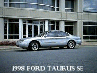 1998 Ford Taurus - A silver 1998 Ford Taurus SE is parked outside a contemporary office building.