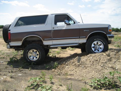 1993 Ford Bronco - This lifted 1993 Ford Bronco features a two-tone brown and white paint scheme and is equipped with all-terrain tires.