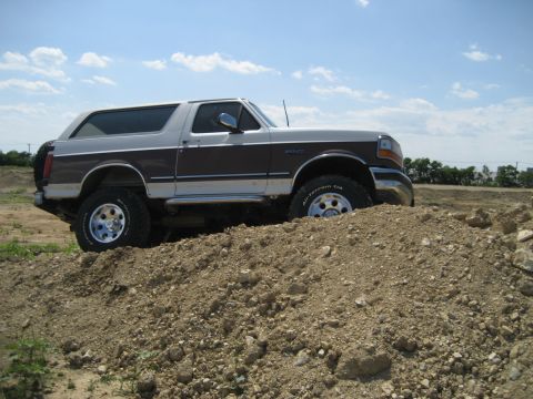 1993 Ford Bronco - This lifted 1993 Ford Bronco with off-road tires navigates a dirt obstacle.