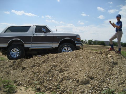 1993 Ford Bronco - 1993 Ford Bronco off-road with a young person in baseball gear observing.