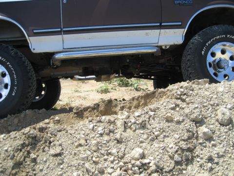 1993 Ford Bronco - 1993 Ford Bronco navigating rough terrain, showing its side profile and off-road tires.
