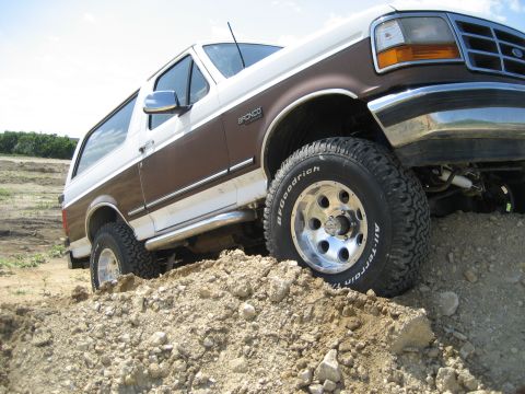 1993 Ford Bronco - This 1993 Ford Bronco is equipped with a lift kit and off-road tires, navigating a dirt terrain.
