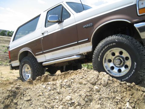 1993 Ford Bronco - This lifted Ford Bronco is shown off-road, navigating a dirt incline with its BFGoodrich All-Terrain tires.