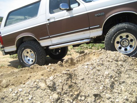 1993 Ford Bronco - This lifted Ford Bronco navigates a dirt terrain with its off-road tires.