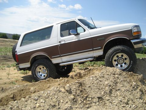 1993 Ford Bronco - This 1993 Ford Bronco is shown off-roading on a dirt pile under a partly cloudy sky.