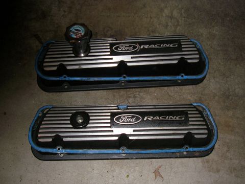 1990 Ford Bronco - Two finned aluminum Ford Racing valve covers with blue gasket edges and a breather, laid on a concrete floor.
