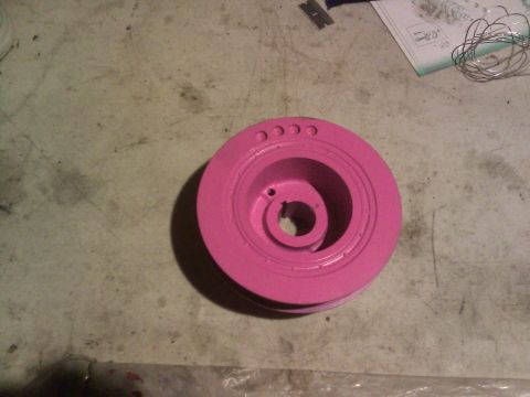 1992 Ford Taurus - A pink crankshaft pulley is shown on a workbench. The part is not identifiable as belonging to a 1992 Ford Taurus.