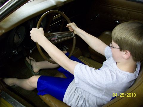 1972 Ford Mustang - A child is seated in the interior of a 1972 Ford Mustang, gripping the steering wheel.