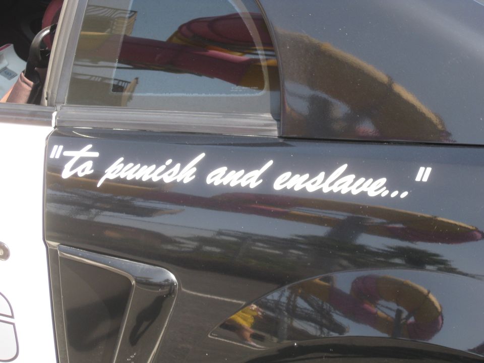 Side of a car with white text that says "to punish and enslave..."