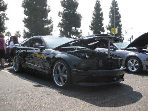 1990 Ford Probe - Two cars are parked outside, one black Mustang with flame decals and its hood open.
