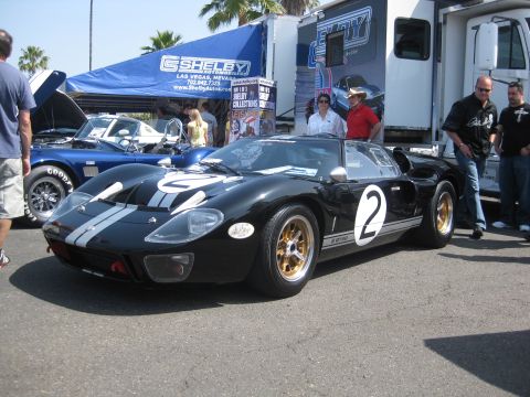1990 Ford Probe - A black Ford GT40 with gold wheels and racing stripes is displayed at an outdoor event, with a blue Shelby Cobra nearby.