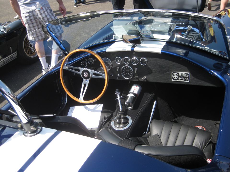 Interior view of a blue sports car with a wooden steering wheel and multiple gauges