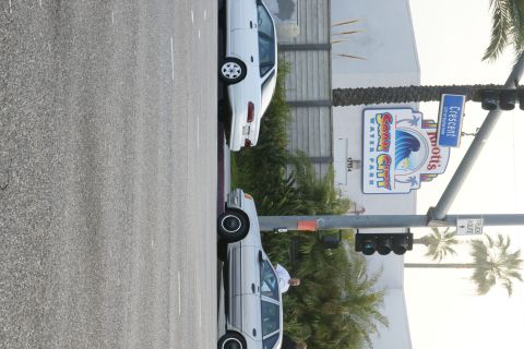 1992 Ford Taurus - Two cars are parked on the side of the road near a water park entrance.