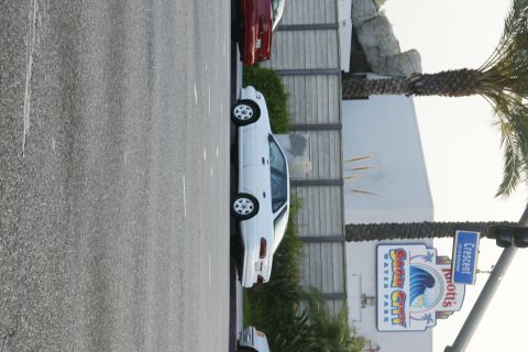 1992 Ford Taurus - A white sedan is parked next to a red car, with a sign for Knott's Soak City Water Park in the background.