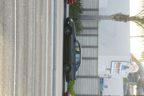 1992 Ford Taurus - A dark sedan is parked in a lot with a Knotts Soak City water park sign visible.