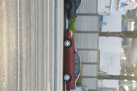 1992 Ford Taurus - A red sedan is parked next to a dark-colored vehicle, with a water park in the background.