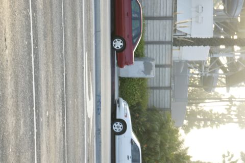 1992 Ford Taurus - Two vehicles are parked on a street next to a concrete barrier and a fence.