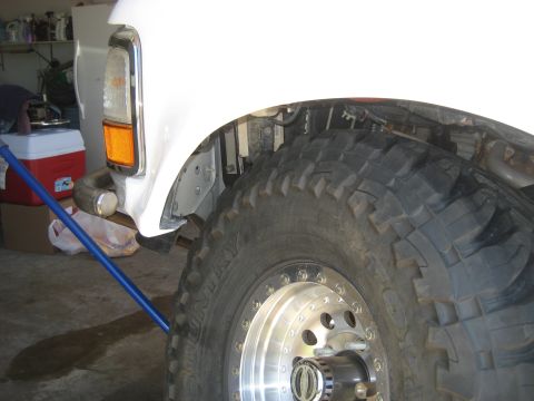 1996 Ford Bronco - Close-up of a white truck's fender and a large off-road tire with a chrome rim.