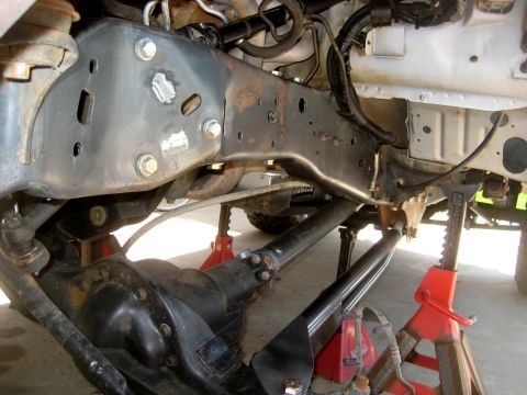 1996 Ford Bronco - Close-up view of a vehicle's front suspension system, including the differential and driveshaft, supported by jack stands.