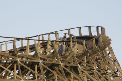 1992 Ford Taurus - Workers are seen on the upper section of a wooden roller coaster, with a clear sky in the background.