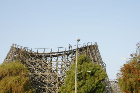 1992 Ford Taurus - A large wooden roller coaster structure dominates the frame against a clear blue sky.