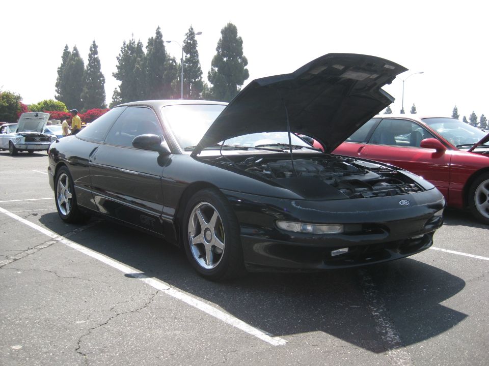 Black 1990 Ford Probe with hood open, parked next to a red car