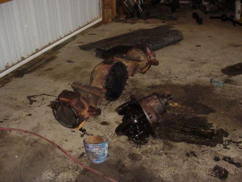 1992 Ford Bronco - Disassembled axles, possibly from a Ford Bronco, lie on a garage floor.