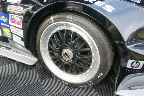 1992 Ford Taurus - Close-up of a racing tire and wheel on a black car, with various sponsor decals visible on the fender.