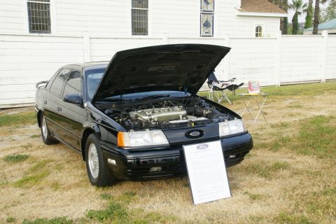 1992 Ford Taurus - Black 1992 Ford Taurus displayed with its hood open at an outdoor event.