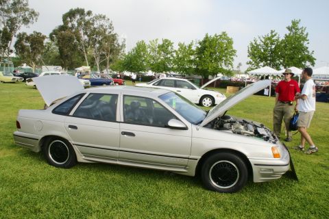 1992 Ford Taurus - Silver sedan with hood and trunk open, parked on grass at an outdoor event.