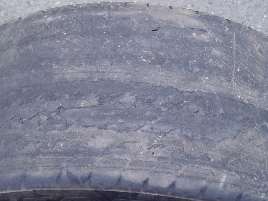 close-up of a very worn tire with cracked sidewalls and minimal tread