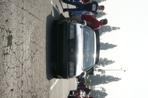 1992 Ford Taurus - A group of people gather around a 1992 Ford Taurus at an outdoor car event.
