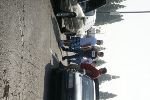 1992 Ford Taurus - A group of people stand around a 1992 Ford Taurus at an outdoor car gathering.
