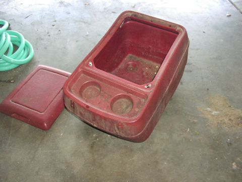 1981 Ford Bronco - A red plastic center console part, likely from a vehicle, is shown with its lid removed and placed beside it.