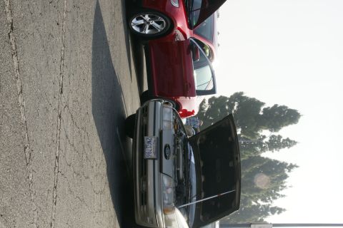 1992 Ford Taurus - Two cars, a silver 1992 Ford Taurus and a red vehicle, are parked with their hoods open.