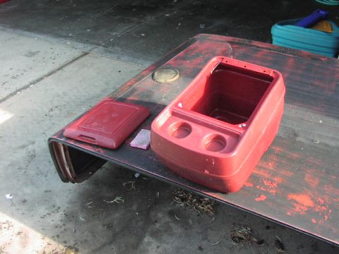 1981 Ford Bronco - Red plastic center console and lid, possibly for a vehicle, shown outdoors.