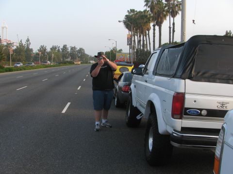 1996 Ford C-350 (Centurion Conversions) - Rear view of a lifted white Ford Bronco parked on the side of a road with other vehicles.