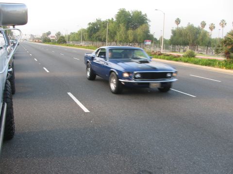 1996 Ford C-350 (Centurion Conversions) - A blue 1969 Ford Mustang Mach 1 is seen driving on a highway next to another vehicle.
