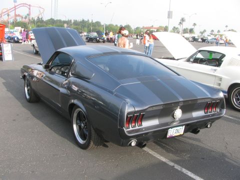 1996 Ford C-350 (Centurion Conversions) - A dark gray 1967 Ford Mustang Fastback with racing stripes is parked at an outdoor event.