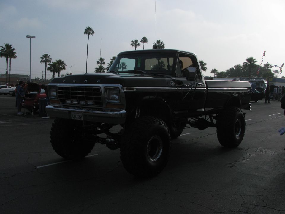 Lifted black Ford pickup truck with large tires, parked outdoors