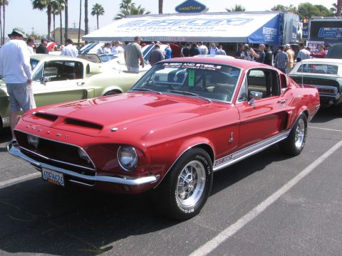 1996 Ford C-350 (Centurion Conversions) - A red 1967 Shelby GT500 Mustang is parked at an outdoor car show with other vehicles visible.